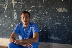 Guy in scrubs sitting against wall